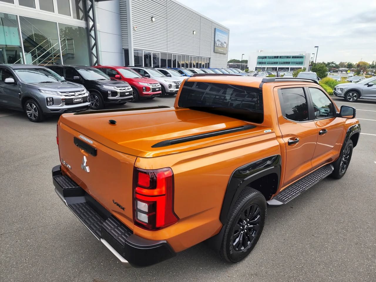 Orange Mitsubishi Triton VRX with the Sport Lid SV at a dealership